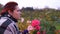 Woman admires a rose in autumn park.