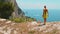 Woman admiring Capri Island with emerald sea waters from the cliff edge. A lone traveler gazes at well-known Faraglioni
