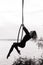 Woman aerialist performs acrobatic elements in hanging aerial hoop against river