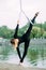 Woman aerialist performs gymnastic split on hanging aerial silk