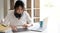 Woman with afro hairstyle remote studying, working online on laptop, chatting with friends via video call on smartphone on tripod