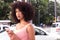 Woman with Afro style frizzy hair in the city during summer, bus