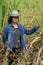 Woman agriculturist standing and catch sugarcane leaf, with straw hat and wearing Long-sleeve denim shirt in sugarcane farm