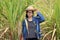 Woman agriculturist standing with her left hand on the hat and wearing Long sleeve denim shirt in the sugarcane farm