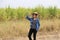 Woman agriculturist standing with right hand on her hat and wearing Long sleeve denim shirt on the sugarcane farm background