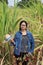 Woman agriculturist standing with straw hat in hand and wearing Long sleeve denim shirt in the sugarcane farm