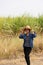 Woman agriculturist standing with two hands on her hat and wearing Long-sleeve denim shirt on the sugarcane farm
