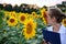 Woman agronomist smelling sunflower in summer field