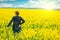 Woman agronomist standing in field of blooming cultivated rapese