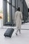 woman at the airport or congress center with a suitcase is sitting in the waiting area and chatting on her smartphone