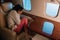 Woman with airsickness covering face while sitting in private jet