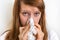 Woman with allergy or flu cold symptoms sneezing in tissue