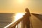 Woman alone contemplating ocean at sunset