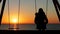 Woman alone swinging contemplating sunset on the beach