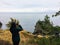 A woman along the coast of Vancouver Island along the east sooke coast trail taking a photo overlooking the wide ocean