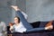 Woman in Anantasana, Side Reclining Leg Lift yoga pose on coach and drinking tea