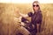 Woman in animal print dress, straw hat in front of Sun in middle of wheat field with pleasure , enjoying summer holidays
