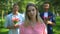 Woman annoyed with male over attention, men holding flowers on background