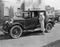 Woman with antique car outside large house