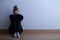 Woman with anxiety disorder wearing dark clothes sitting on the floor, copy space on empty wall