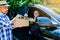 Woman appending signature sign on tablet after accepting receive boxes from delivery man in black car