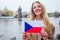 Woman with an appetite eats a traditional The Charles Bridge and wawing with flag