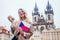 Woman with an appetite eats a traditional Czech sweet Trdelnik in street Prague s Old Town Square and wawing with flag