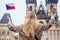 Woman with an appetite eats a traditional Czech sweet Trdelnik in street Prague s Old Town Square and wawing with flag