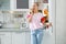 Woman with apple standing near open refrigerator