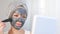 A woman applies a cleansing mask to her face