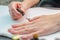 A woman applies a primer to her nails before applying varnish. Close-up of a hand.