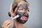 Woman Applying Activated Charcoal Face Mask With Brush