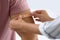 Woman applying adhesive  on man`s arm against light background, closeup