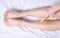 Woman applying body spray on her leg in bedroom closeup