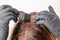 Woman applying a color tint to the brown hair using a brush. Dyeing of gray roots of hair at home.