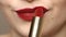 Woman applying deep red lipstick on the lips.  Close up view of beauty and fashion concept