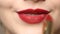 Woman applying deep red lipstick on the lips.  Close up view of beauty and fashion concept