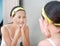 Woman applying foam cream to face reflect with bathroom mirror