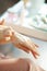 Woman applying hand cream in house in sunny winter day