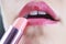 Woman applying light pink lipstick