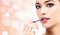 Woman applying lips makeup with cosmetic brush