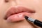 Woman applying lipstick on lips