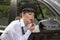 Woman applying lipstick looking in car wing mirror