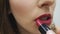 Woman applying lipstick. Makeup in process. Woman painting red lipstick. Female hand holding tube of lipstick. Slow motion