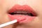 Woman applying liquid lipstick cream to her lips. Close up