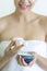 Woman applying Moisturizer cream or Scrub Lotion on hands treatment in spa salon