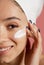 Woman applying moisturizing cream on her face