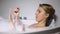 Woman applying nail polish during bathing with foam bubbles, beauty procedure