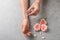 Woman applying rose essential oil on wrist and flowers at grey table