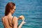 Woman applying sunscreen creme on tanned shoulder over the sea